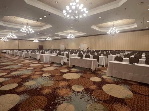 a banquet hall with white tables and chairs and chandeliers at Lynchburg Grand Essential by IHG in Lynchburg
