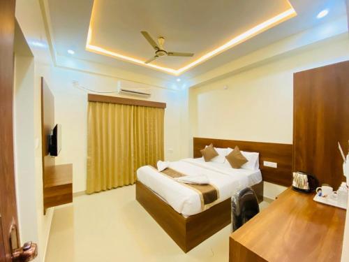 a bedroom with a bed and a table and a ceiling at Hotel SAFKO Grand - Hopefarm Metro Whitefield in Bangalore