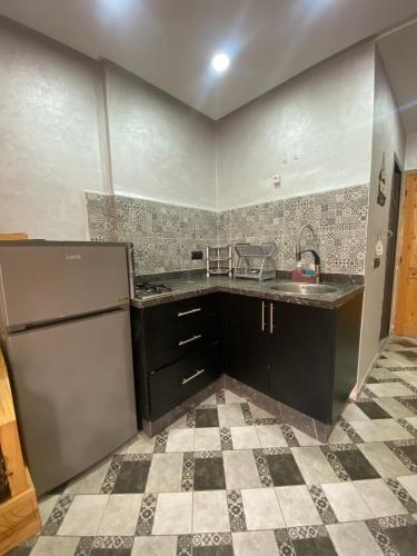 a kitchen with black cabinets and a tile floor at summer house berber in Tamraght Ouzdar