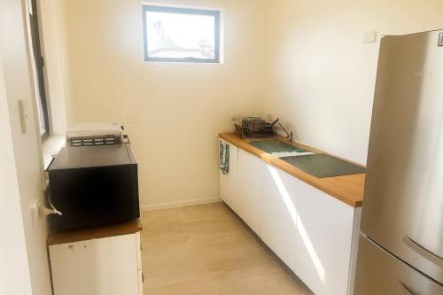 a small kitchen with a counter and a refrigerator at New & Stylish Veg 2-Bedroom Guest Retreat Near Brisbane Airport in Brisbane
