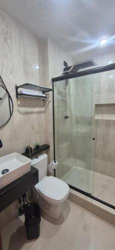 a bathroom with a shower and a toilet and a sink at Suites Novas in Cabo Frio