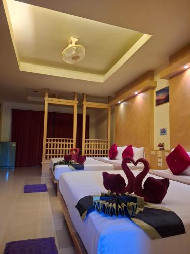 ein Hotelzimmer mit drei Betten mit Schwänen darauf in der Unterkunft Lanta Summer House 1 in Ko Lanta