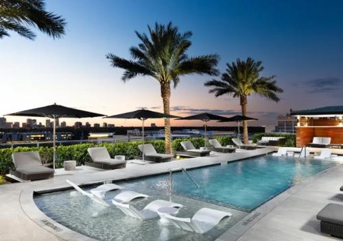 een zwembad met stoelen, parasols en palmbomen bij Hanover River Oaks in Houston