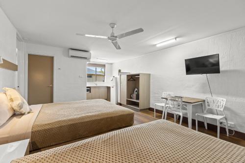 Broome Time Resort في بروم: غرفة نوم بسريرين وطاولة وتلفزيون