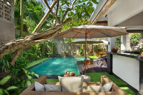 an outdoor patio with an umbrella and a swimming pool at Red Lotus Seminyak Villa in Seminyak