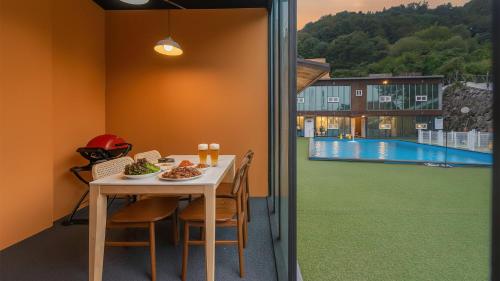 een eetkamer met een tafel en uitzicht op een zwembad bij Gapyeong Santa Maria Dog-friendly Privat in Gapyeong