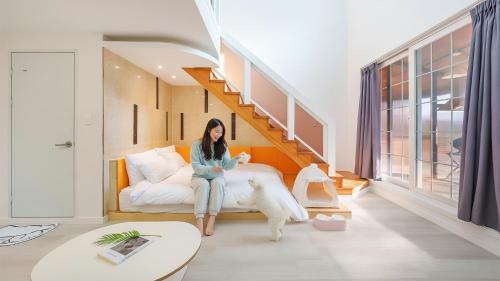 a woman sitting on a bed with a dog in a room at Gapyeong Santa Maria Dog-friendly Privat in Gapyeong