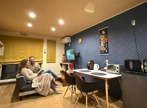 a man and a woman sitting in a room at Vieuno Hida Takayama -Live Locally in Cozy Rooms near Takayama Station! in Takayama