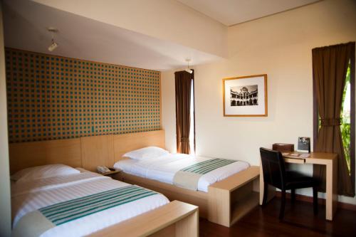 - une chambre avec deux lits, un bureau et une chaise dans l'établissement Java Go Residence by Jiwa Jawa, à Semarang