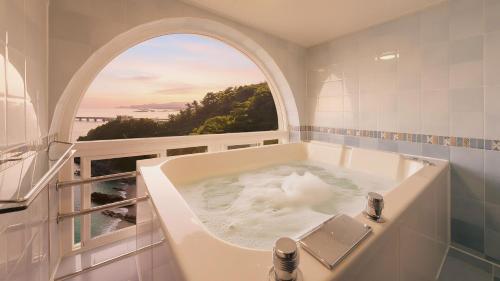 Un baño con bañera y ventana. en Samcheok Peacehousing Spa Pet Pension, en Samcheok