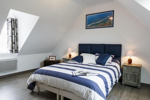 Un dormitorio con una cama azul y blanca y una ventana. en La fringante, en Pleubian