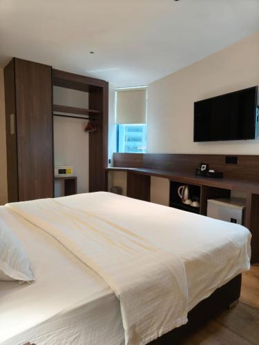 a bedroom with a large white bed and a flat screen tv at The Imperial Hotel in Kluang