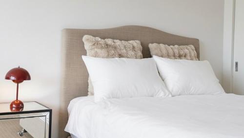 a bedroom with a white bed with white pillows at Stunning Harbour Bridge Views Apartment in Sydney