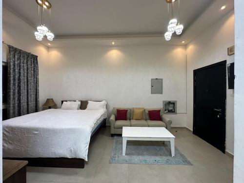Un dormitorio con una cama, un sofá y una mesa. en Entire Studio Apartment Beside Oasis towers, en Ajman
