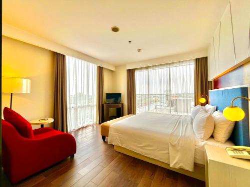 Una habitación de hotel con una cama y una silla roja. en Amandaru Hotel Pekalongan, en Pekalongan