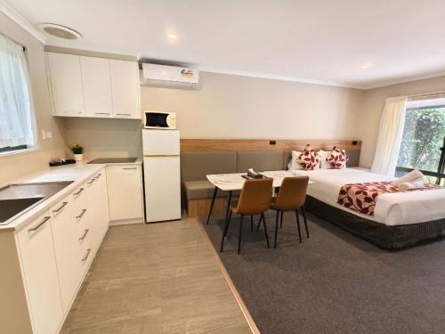 a bedroom with a bed and a table and a kitchen at Coachman Motel and Holiday Units in Cowes