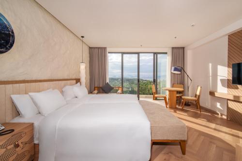 um quarto de hotel com uma cama grande e uma televisão em Hoi An Beachfront 5 star Resort & Apartment em Dien Ban