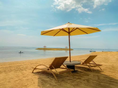 zwei Stühle und ein Sonnenschirm am Strand in der Unterkunft eL Hotel & Resort Bali Sanur in Sanur