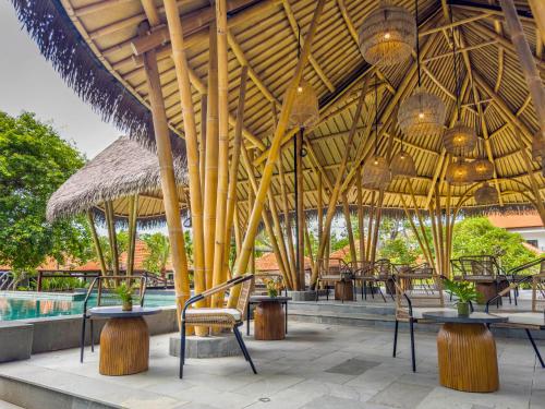 ein Pavillon mit Tischen und Stühlen und ein Pool in der Unterkunft eL Hotel & Resort Bali Sanur in Sanur