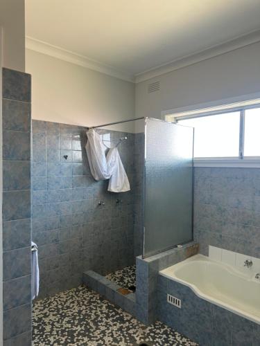 a bathroom with a tub and a shower with a tub at 80 Tarcutta St in Wagga Wagga