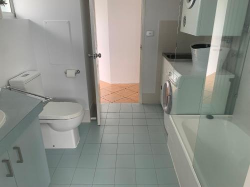 a white bathroom with a toilet and a sink at Ocean Plaza Resort in Gold Coast