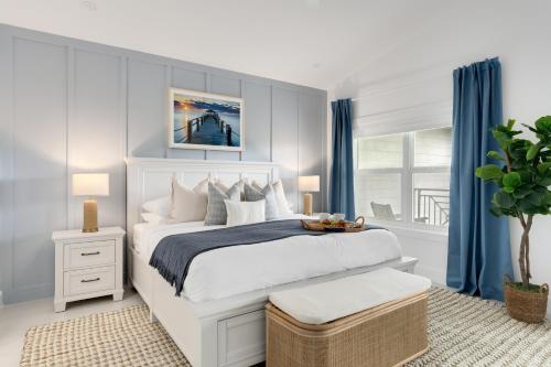 ein Schlafzimmer mit einem weißen Bett und blauen Vorhängen in der Unterkunft Oceanfront Luxury w/Speakeasy Lounge, Dock & Pool in Islamorada