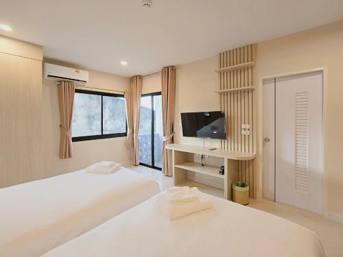 een witte slaapkamer met 2 bedden en een televisie bij Maraya Residence มารอยา เรสซิเดนซ์ in Bang Bua Thong