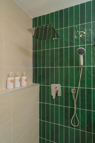 a green tiled bathroom with a shower with an umbrella at Baansiwalin in Phra Nakhon Si Ayutthaya