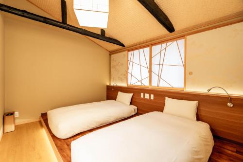 deux lits dans une chambre avec deux fenêtres dans l'établissement Machiya Izumi higashiyama, à Kyoto