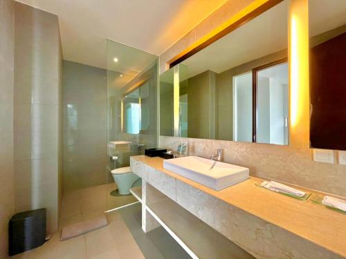 Un baño con lavabo y un espejo grande. en Amandaru Hotel Pekalongan, en Pekalongan