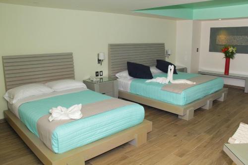 duas camas num quarto com dois cisnes em Villas Maria Isabel em Santa Cruz, Huatulco