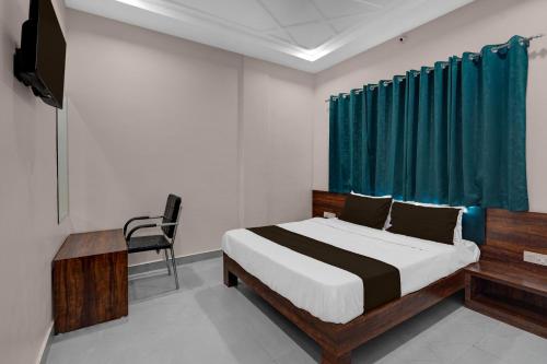 a bedroom with a bed and a chair and a television at Super Hotel O Kota Railway Junction Formerly Formerly Aagam Inn in Kota