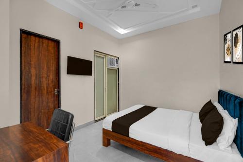 a bedroom with a bed and a desk and a door at Super Hotel O Kota Railway Junction Formerly Formerly Aagam Inn in Kota