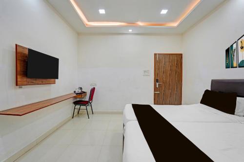 a bedroom with a bed and a tv on the wall at Super Townhouse Vanagaram Apollo Hospital Chennai Formerly V Hotels & Restaurant in Chennai
