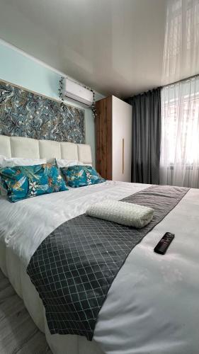 a bedroom with a large bed with a remote control on it at Shymkent plaza 3 in Shymkent