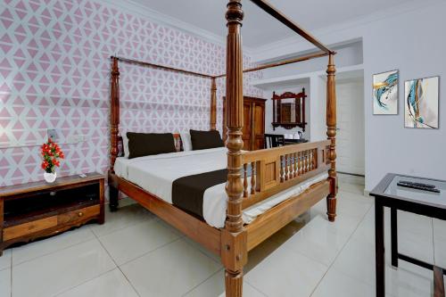 Un dormitorio con una cama con dosel de madera y un escritorio. en Collection O Sunrise Point Serenity Beach Formerly White Lotus Residency, en Kottakupam