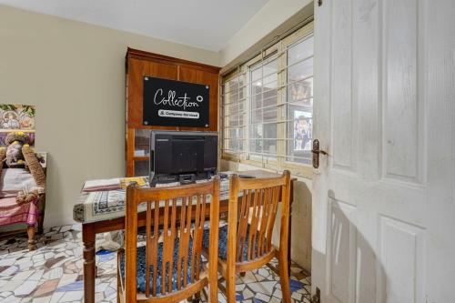 a kitchen with two chairs and a table with a television at Collection O Sunrise Point Serenity Beach Formerly White Lotus Residency in Kottakupam