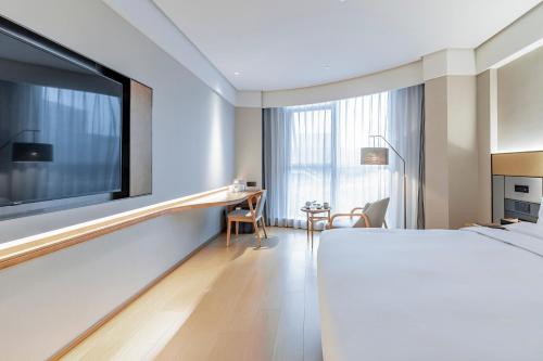 a hotel room with a large bed and a desk at JI Hotel Shanghai Pudong Airport Zhuqiao in Nanhui
