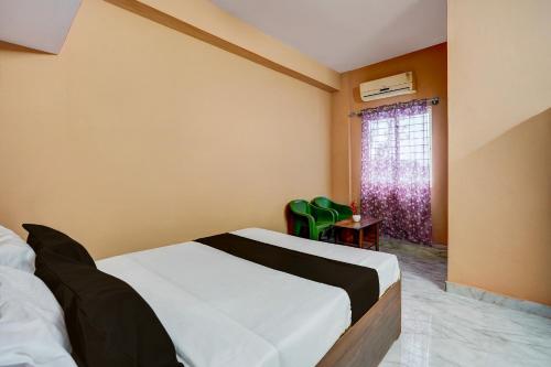 a bedroom with a bed and a window with green chairs at Hotel O Bidadi Railway Junction Bangalore Formerly Ejalla in Bidadi