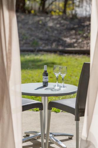 a table with two wine glasses and a bottle on it at Hunter Gateway Motel in Maitland