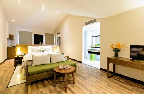 a bedroom with a bed and a table and a television at Lasenta Boutique Hotel Hoian in Hoi An