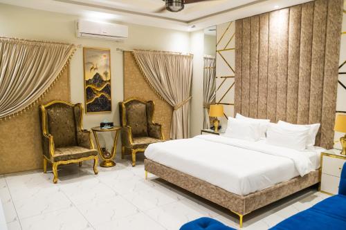 een slaapkamer met een bed en twee stoelen bij Karachi Fort Boutique Hotel in Karachi
