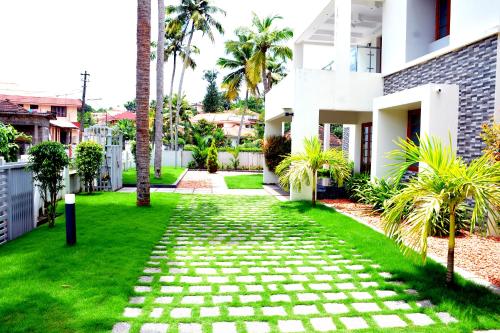 a walkway in front of a house with palm trees at Shamrock Home Stay (5-Bedroom Bungalow) in Thiruvalla