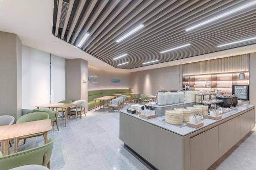 a restaurant with tables and chairs and a cafeteria at JI Hotel Shanghai Pudong Airport Zhuqiao in Nanhui