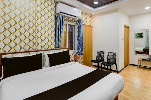 Un dormitorio con una cama grande y dos sillas. en Collection O Kollur Prime Arena Formerly Hotel Krishna, en Kundakal