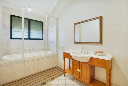 een badkamer met een wastafel, een bad en een spiegel bij Kingfisher Vista in Cable Beach
