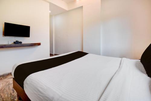 um quarto com uma cama e uma TV na parede em Super Hotel O Khadakwasla Lakeview Formerly Gokul Lodge em Kharakvasla