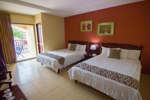 a hotel room with two beds and a balcony at Gran Hotel Azuero in Chitré
