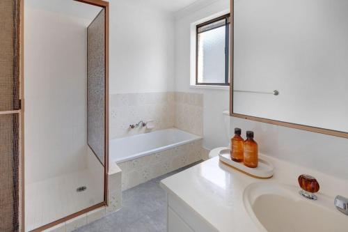 ゴールドコーストにあるPalm Springs Waterfront Retreat - Broadbeach Watersの浴槽、洗面台、鏡のあるバスルーム