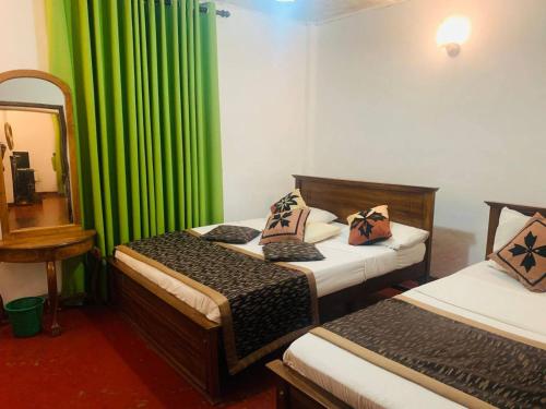 1 dormitorio con 2 camas y cortina verde en Lady Maccllum's Bungalow Stone Nuwareliya Sri Lanka, en Nuwara Eliya
